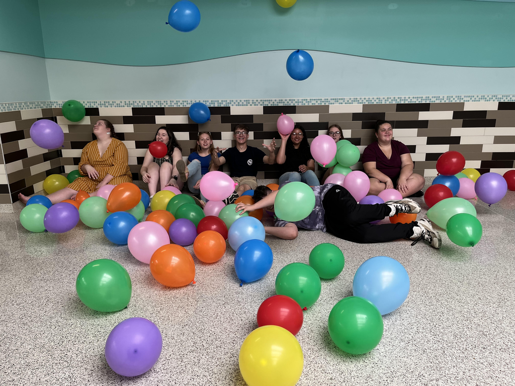 Members of the Freshman Class sitting on the floor surrounded by colorful balloons.